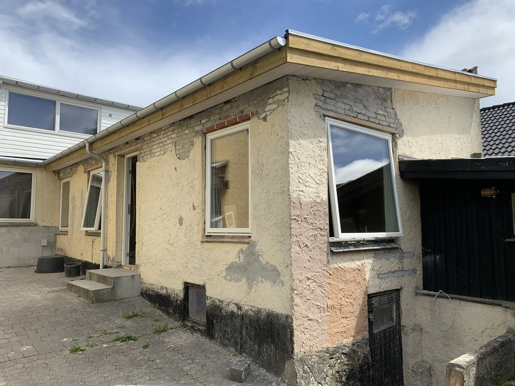 Huset på Eberlinsvej med lukket tag, tagrender og udhæng, mens facaden stadig er under færdiggørelse