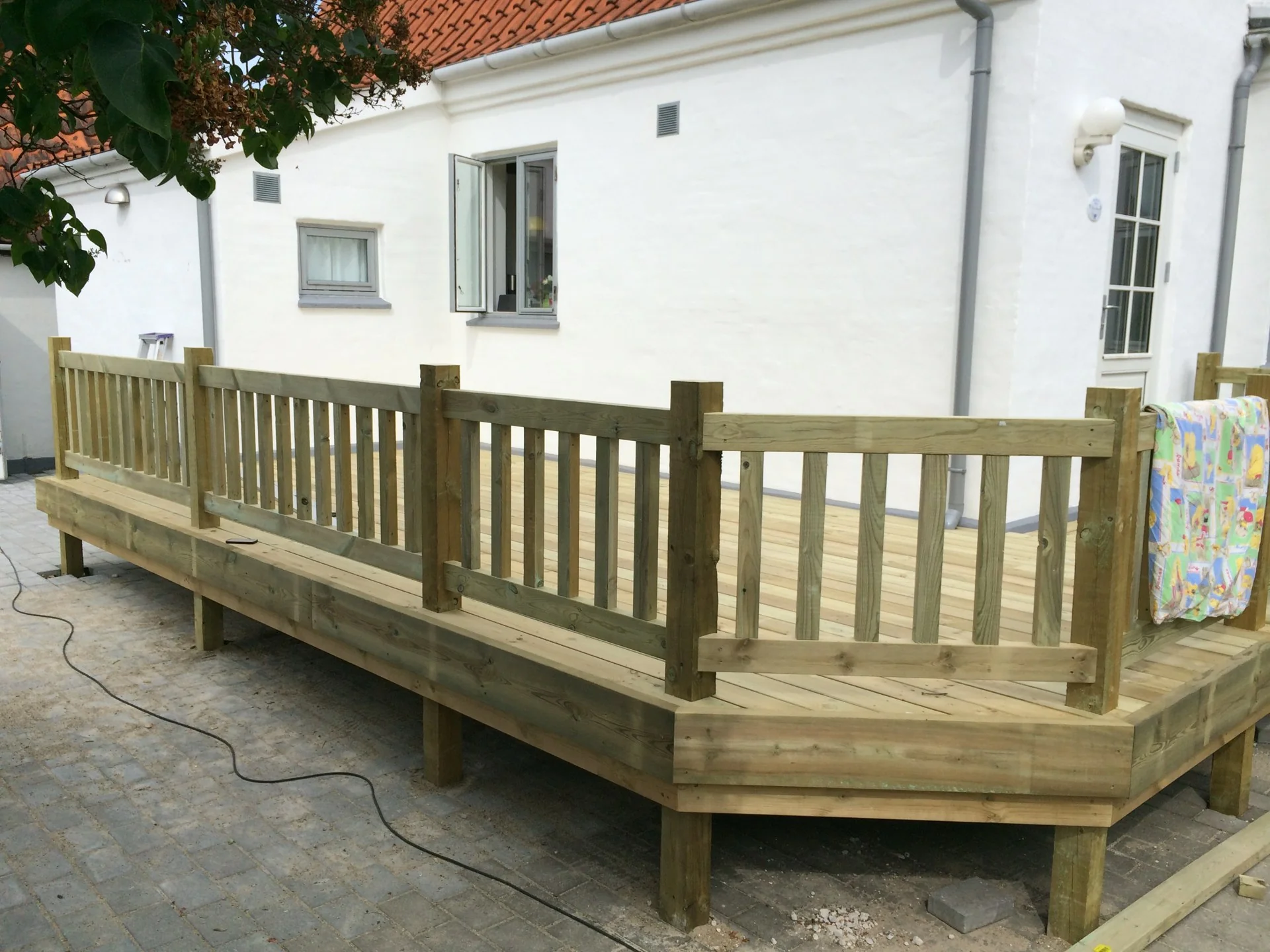 Hævet terrasse i trykimprægneret træ med gelænder ved et hvidt hus i Hillerød